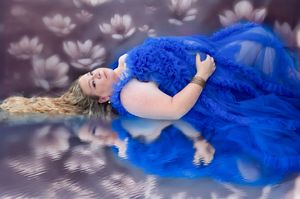 Artistic maternity photos featuring a flowing blue dress against a dreamy floral background.