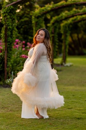 Flowing white dress spins gracefully on a grassy lawn at golden hour.