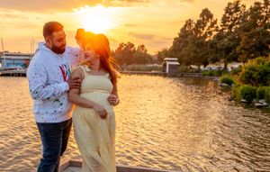 A couple enjoys a romantic sunset moment by the water's edge with golden light.