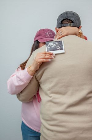 Two people hold up a sonogram photo while embracing in an emotional pregnancy announcement.