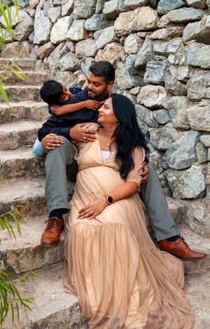 A couple shares tender moments on stone steps in a romantic photoshoot while wearing a peach-colored dress.