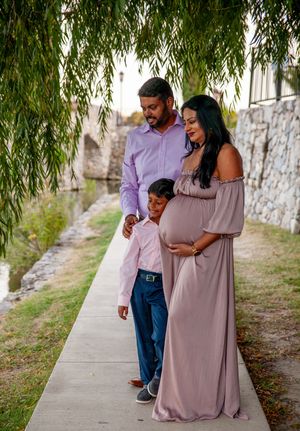 Casual maternity photos under willow trees showing playful moments in mauve dress.