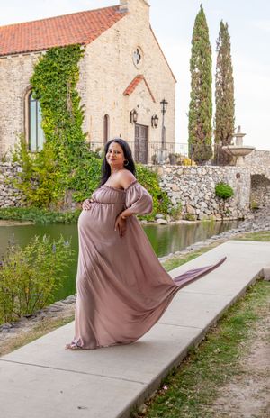 Flowing mauve dress maternity portraits showcasing graceful poses by historic stone church.