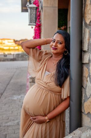 Maternity portrait session at sunset featuring neutral toned dress and architectural columns.