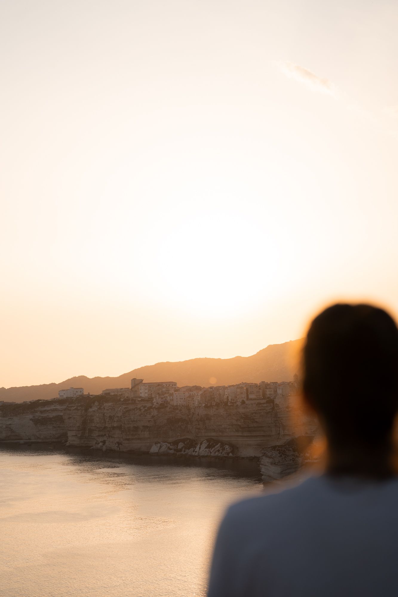 femme qui observe le coucher du soleil sur les falaises de bonifacio