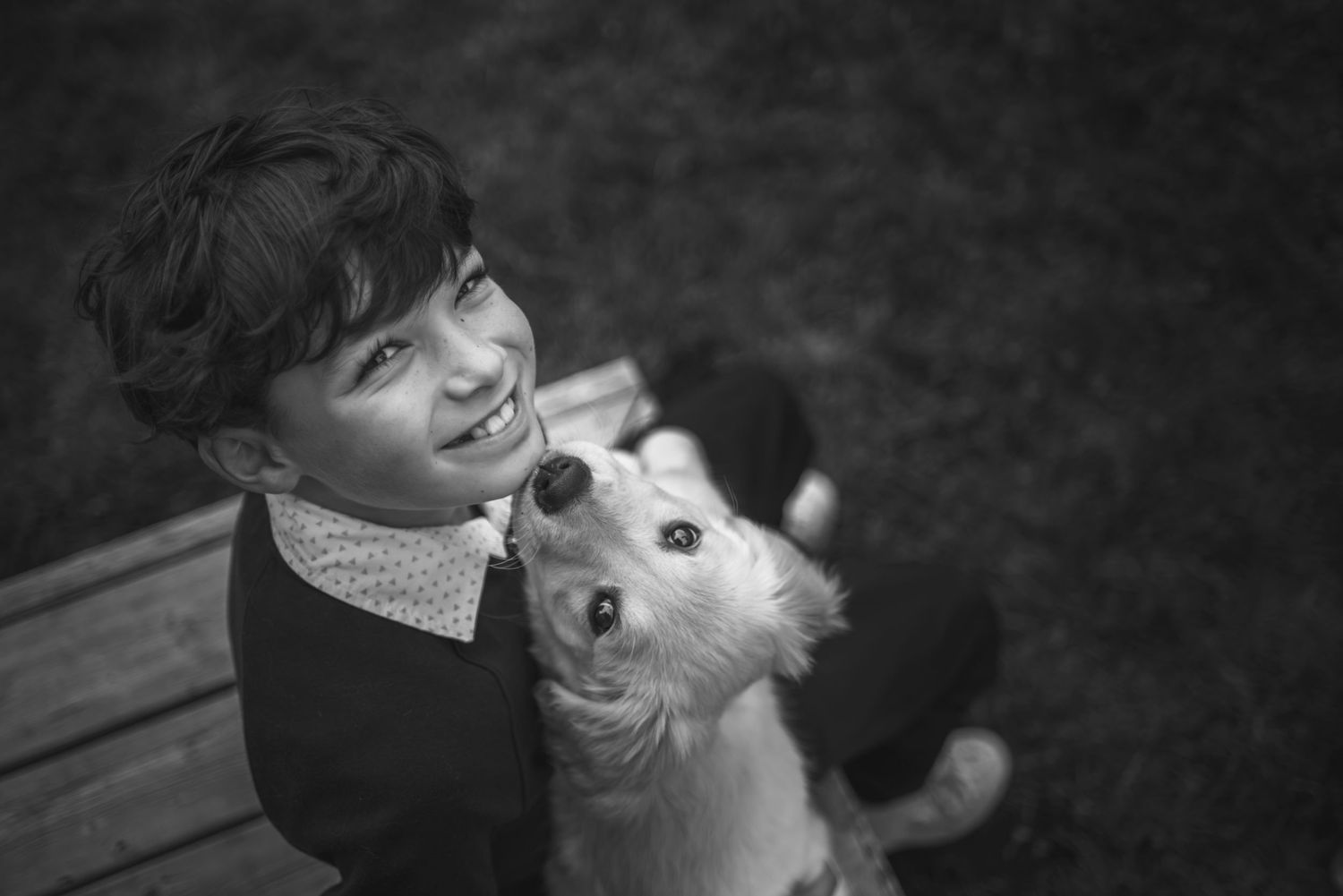 Black and white showing joyful interactions between a young child and a puppy.