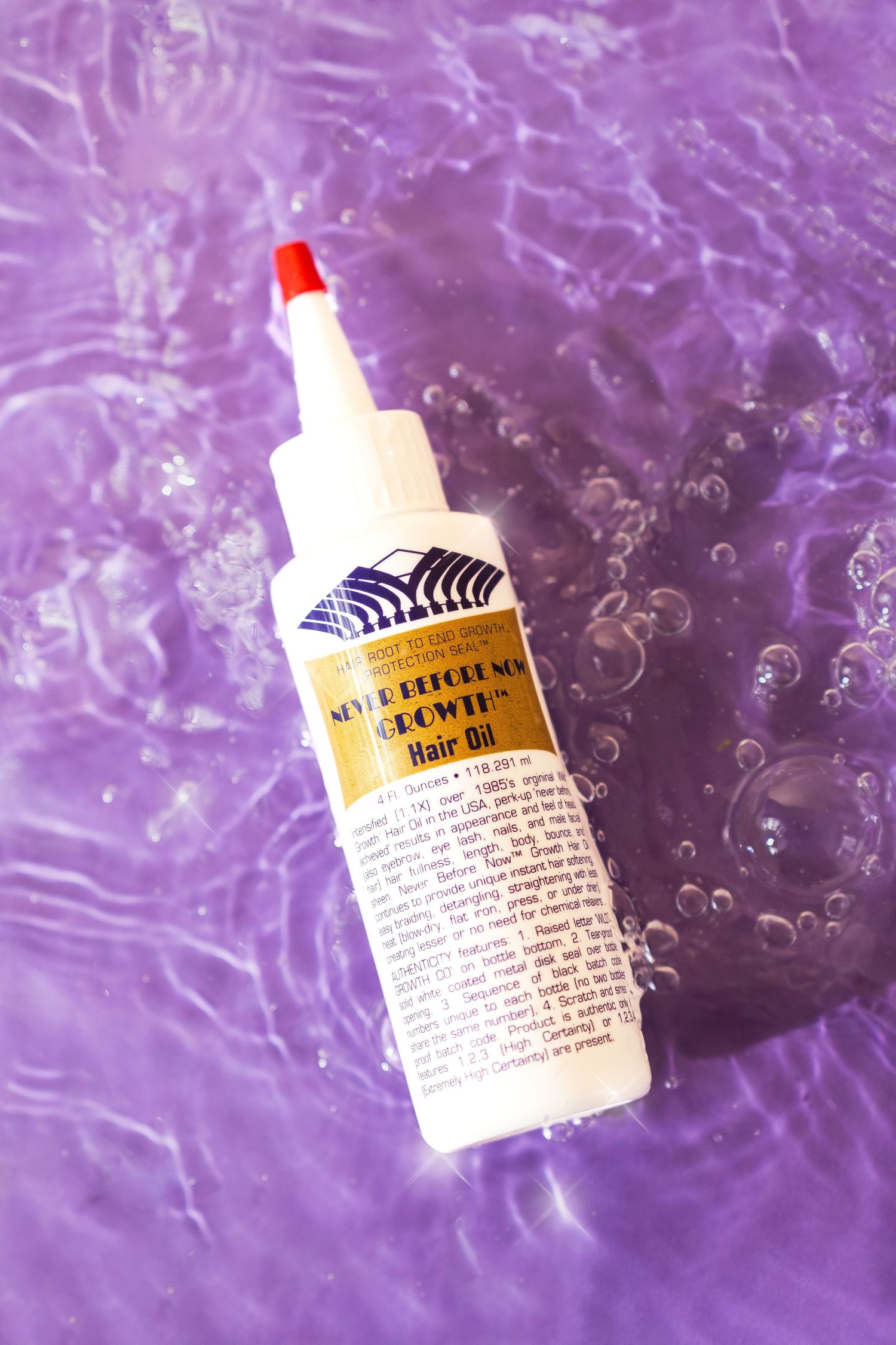 Hair oil container floating on a sparkling purple water backdrop.