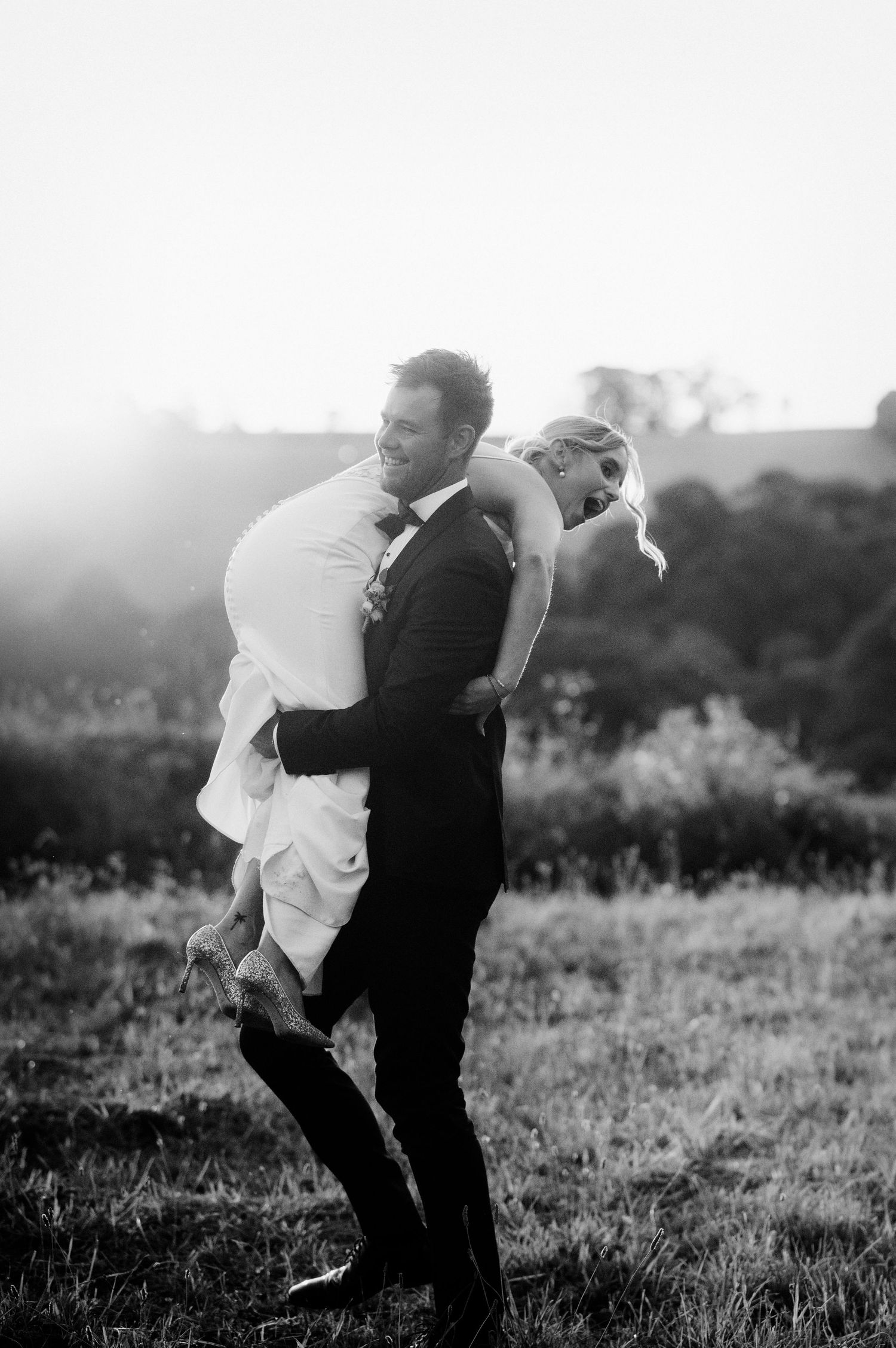 Black and white photo series showing a wedding couple walking away together across a sunlit meadow in vintage style.
