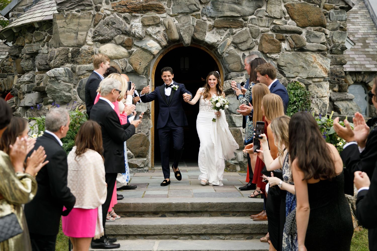 Stone wall courtyard filled with wedding guests during outdoor celebration.