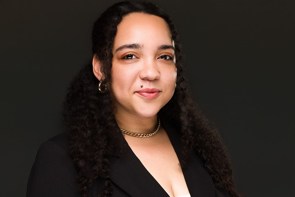 Professional business headshot portrait against a dark background with warm and friendly demeanor.