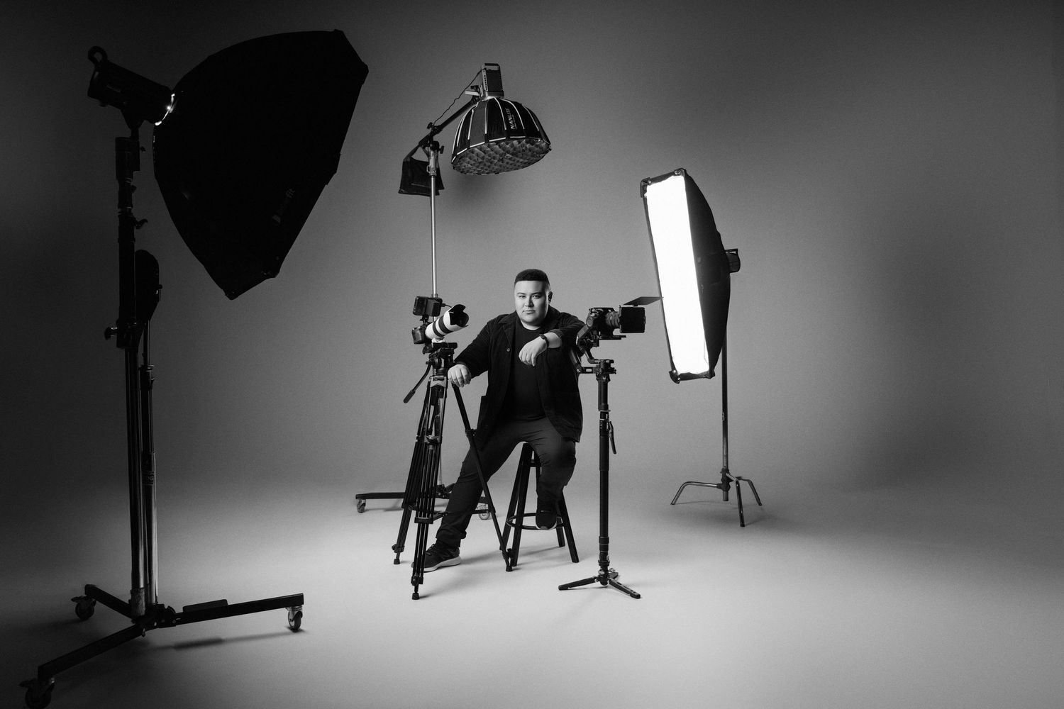 Black and white photo from professional photo studio setup showing lighting equipment and silhouettes on a seamless backdrop.