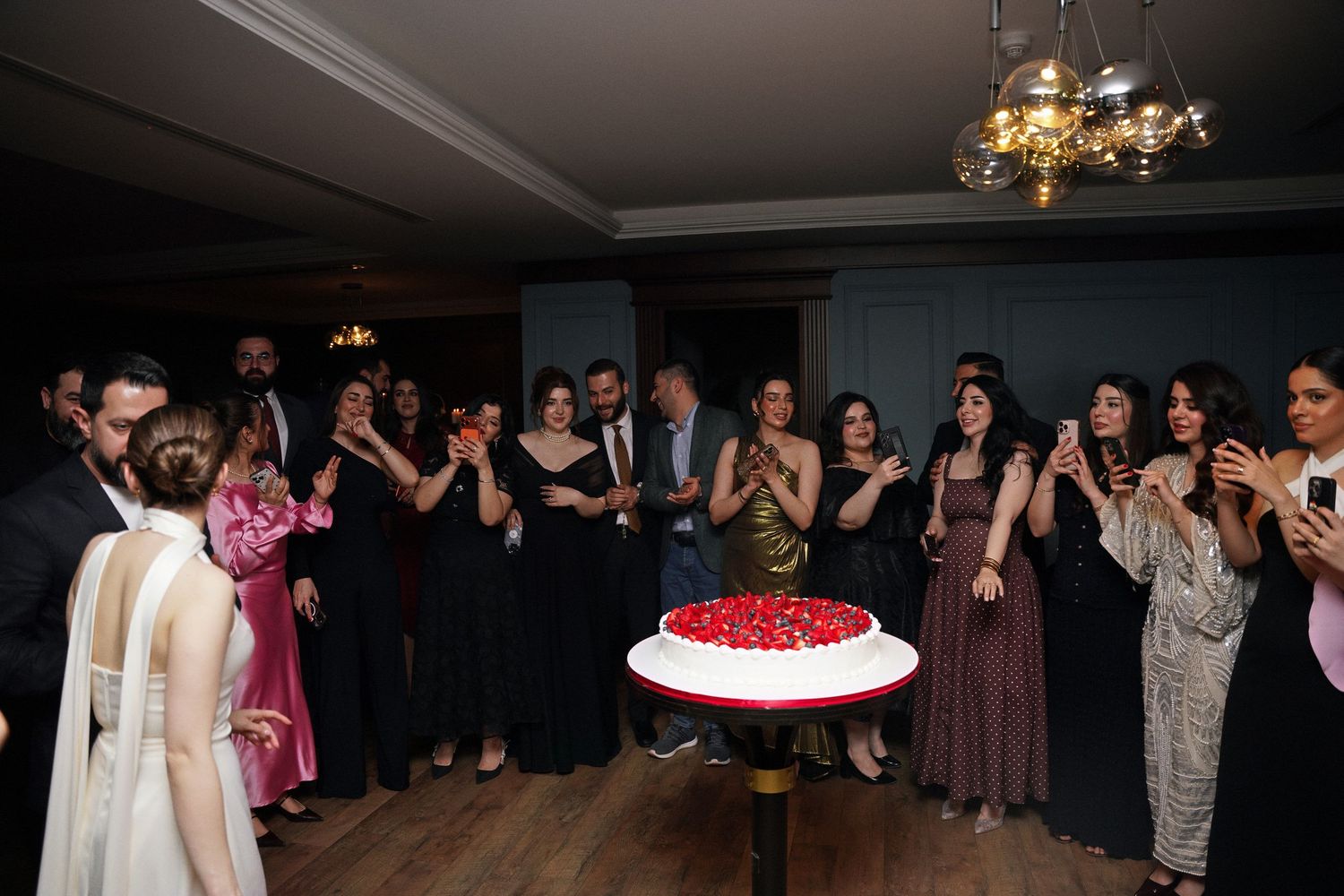 Wedding guests raise champagne glasses in a toast during celebration under glowing green lights at reception.