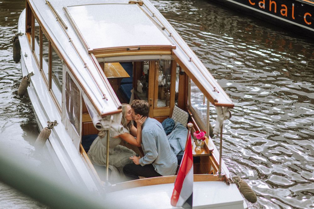 Tour boats navigating through Amsterdam's scenic canals on a sunny day.