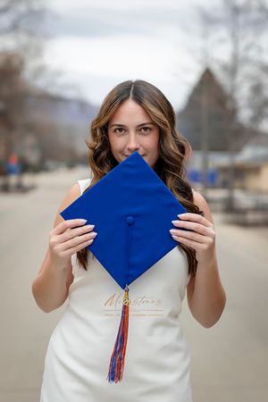 Boise State University graduate of nursing  wearing white dress and holding cap