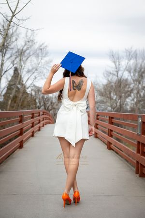 Boise State University graduate of nursing  wearing white dress and blue cap facing away from camera showing off back tattoo of a butterfly