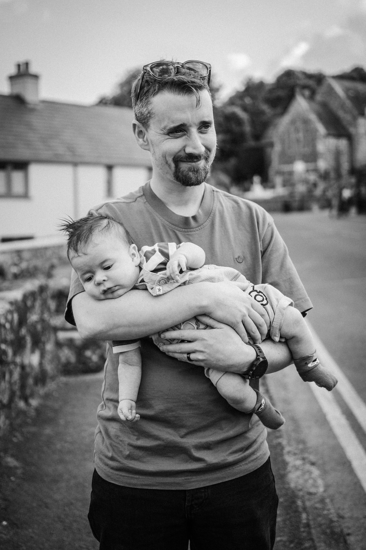 Black and white photo series showing a parent holding and playing with a small baby outdoors.