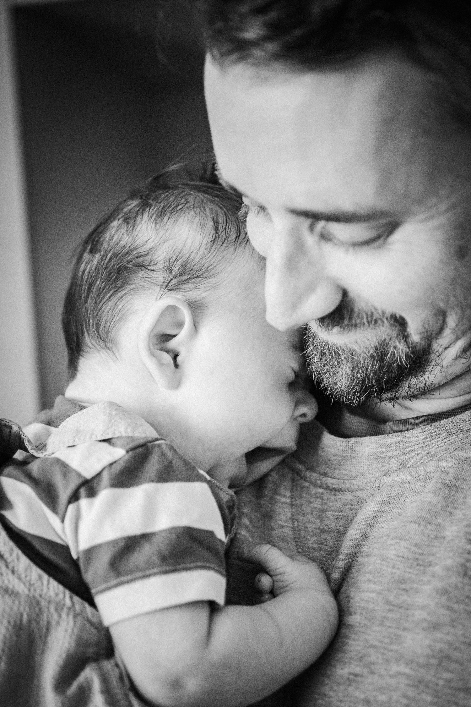 A tender black and white photo series showing a baby and bearded adult sharing sweet moments together.