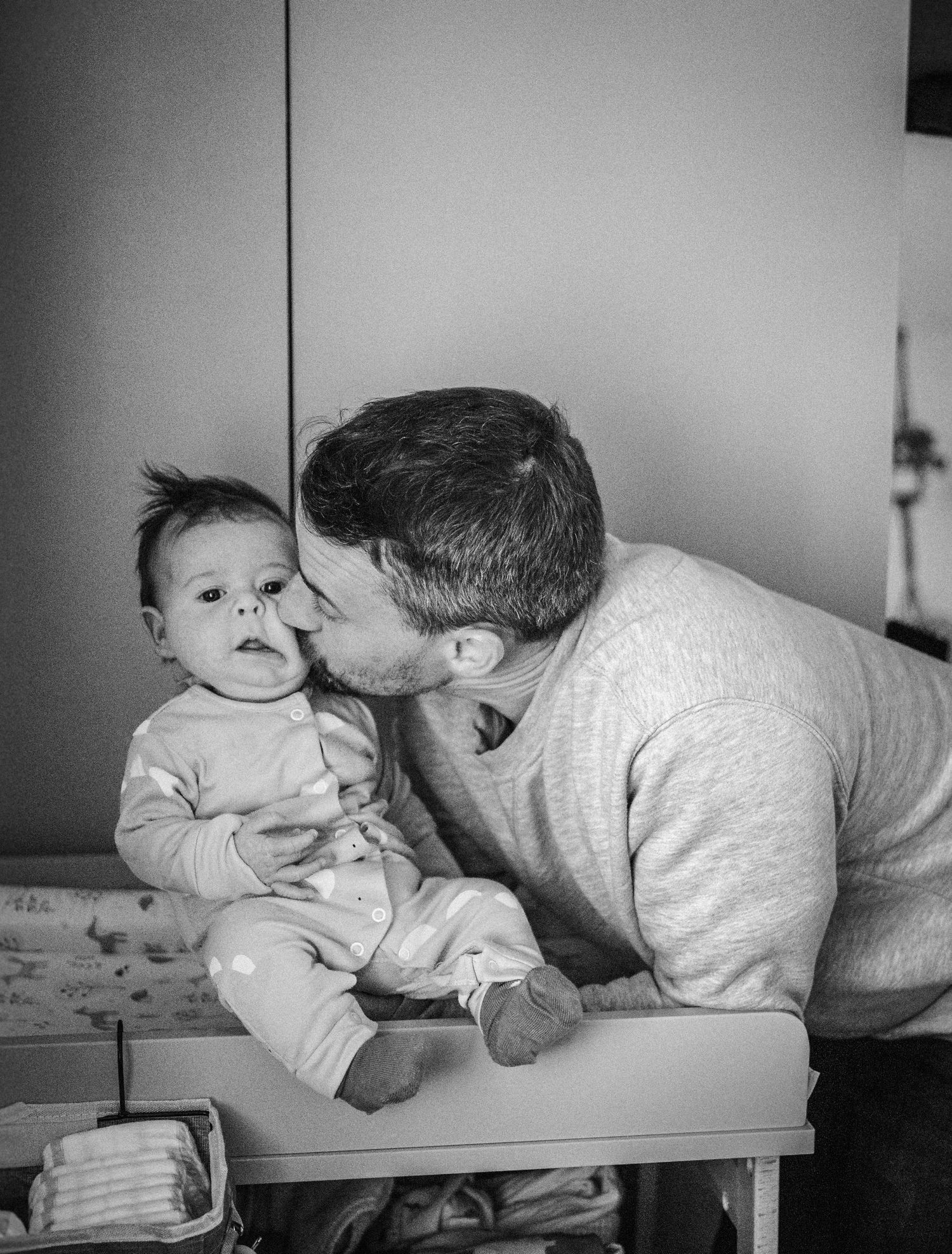 A tender black and white sequence shows a parent and baby sharing playful moments on a changing table.