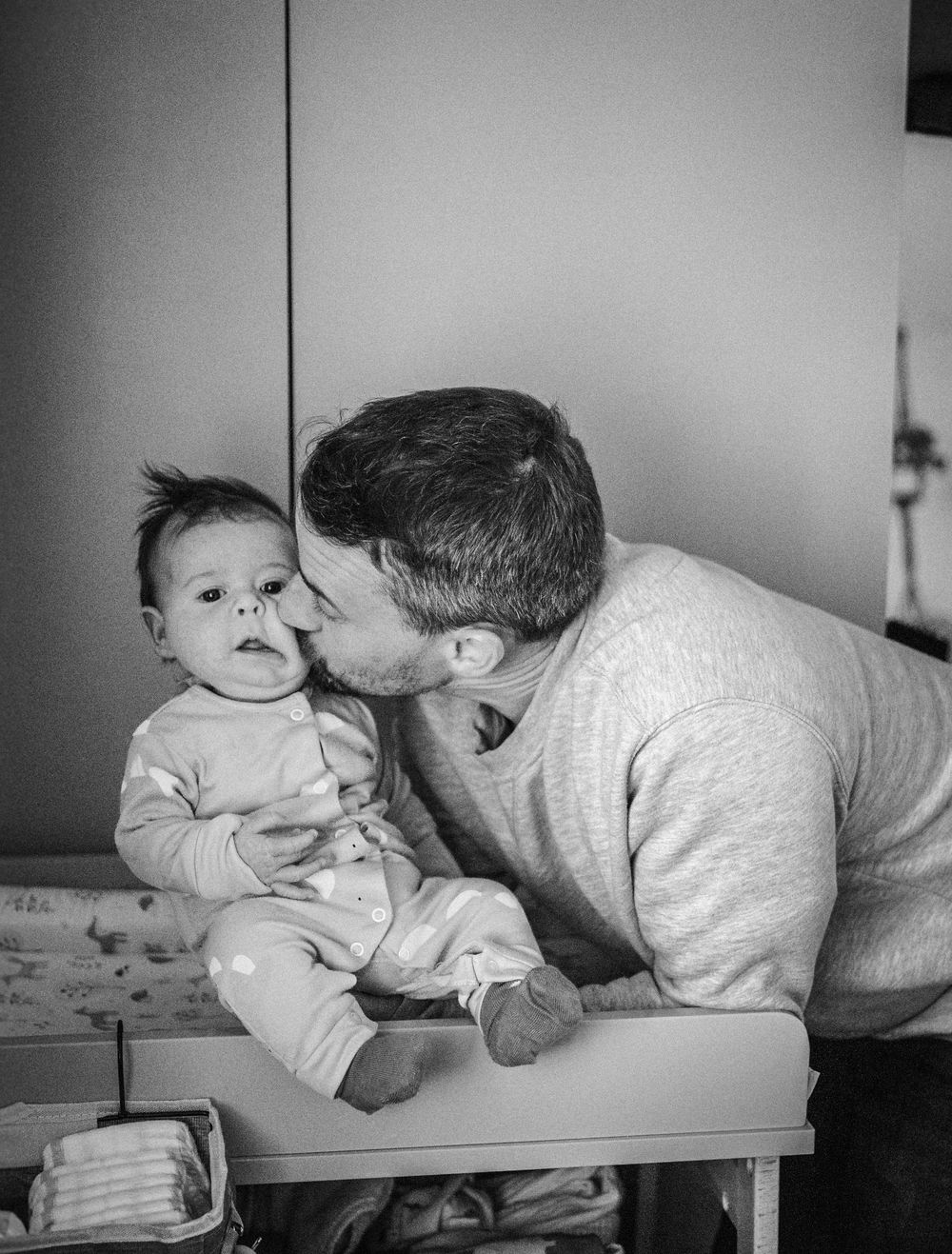 A tender black and white sequence shows a parent and baby sharing playful moments on a changing table.