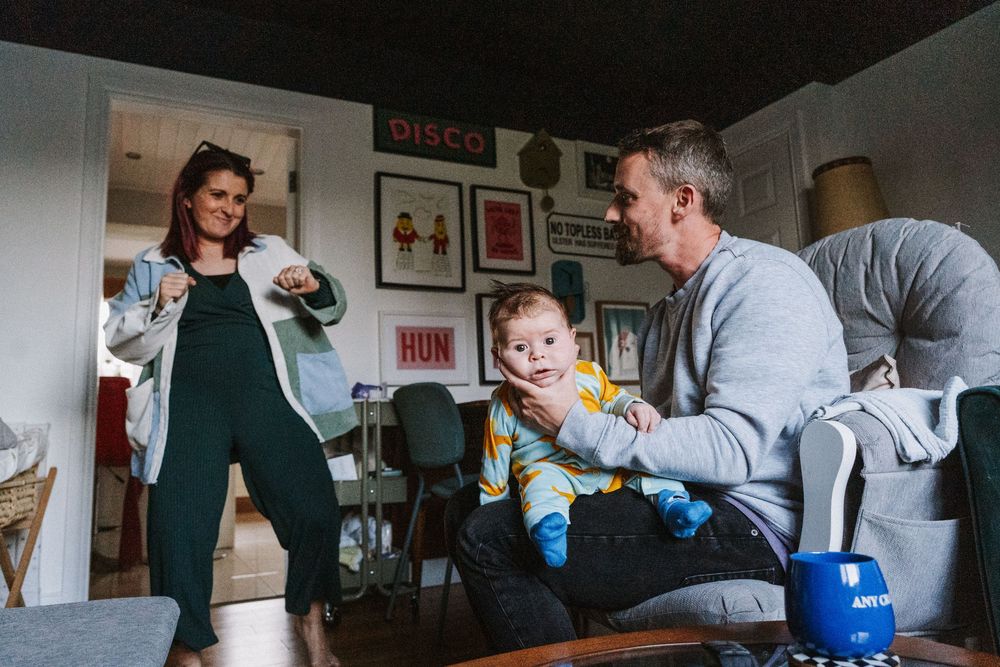 A parent and child play together with toys while sitting on a couch in a living room.
