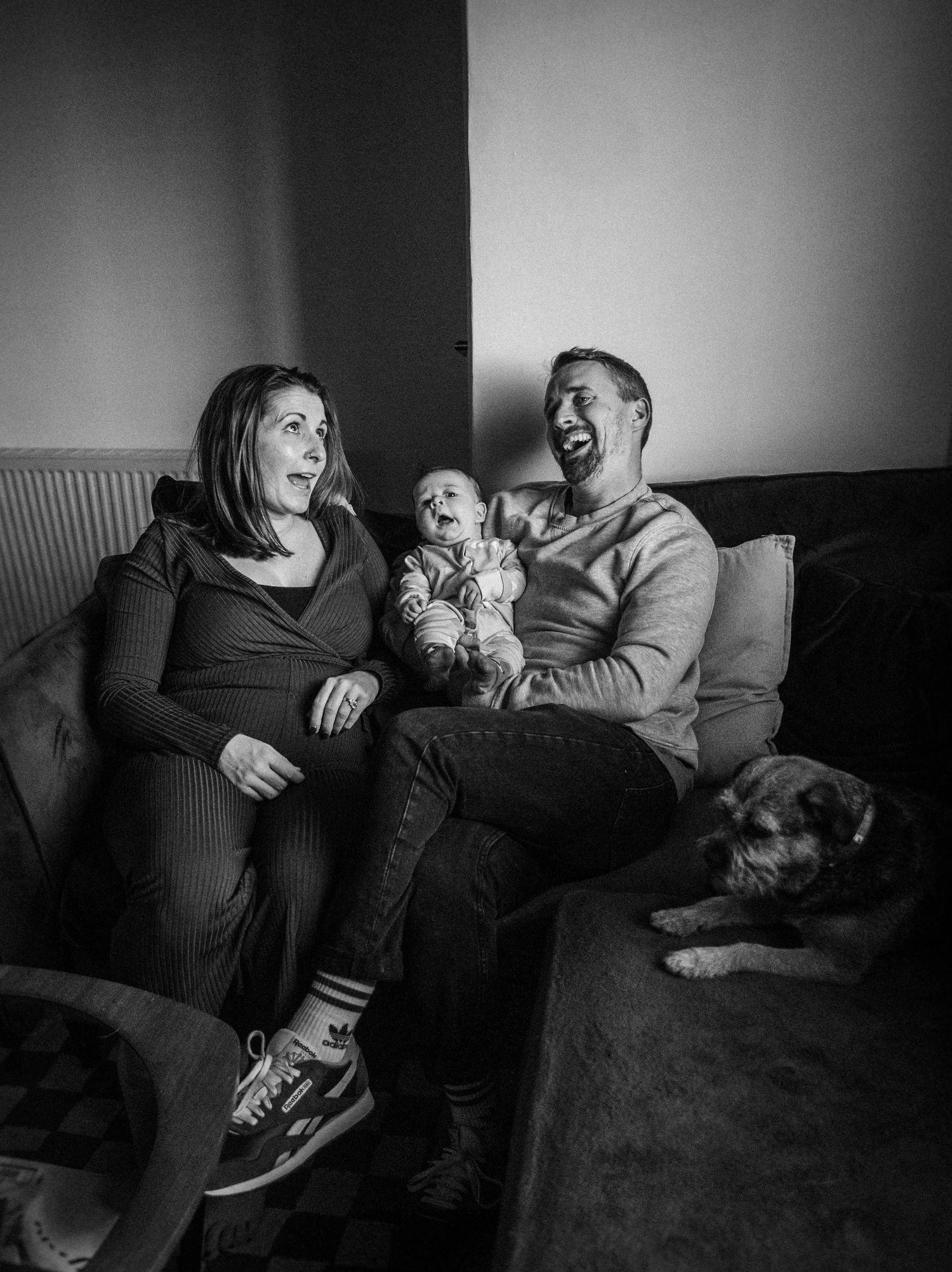 A series of black and white photos showing a family sharing joyful moments and laughter together on a couch.