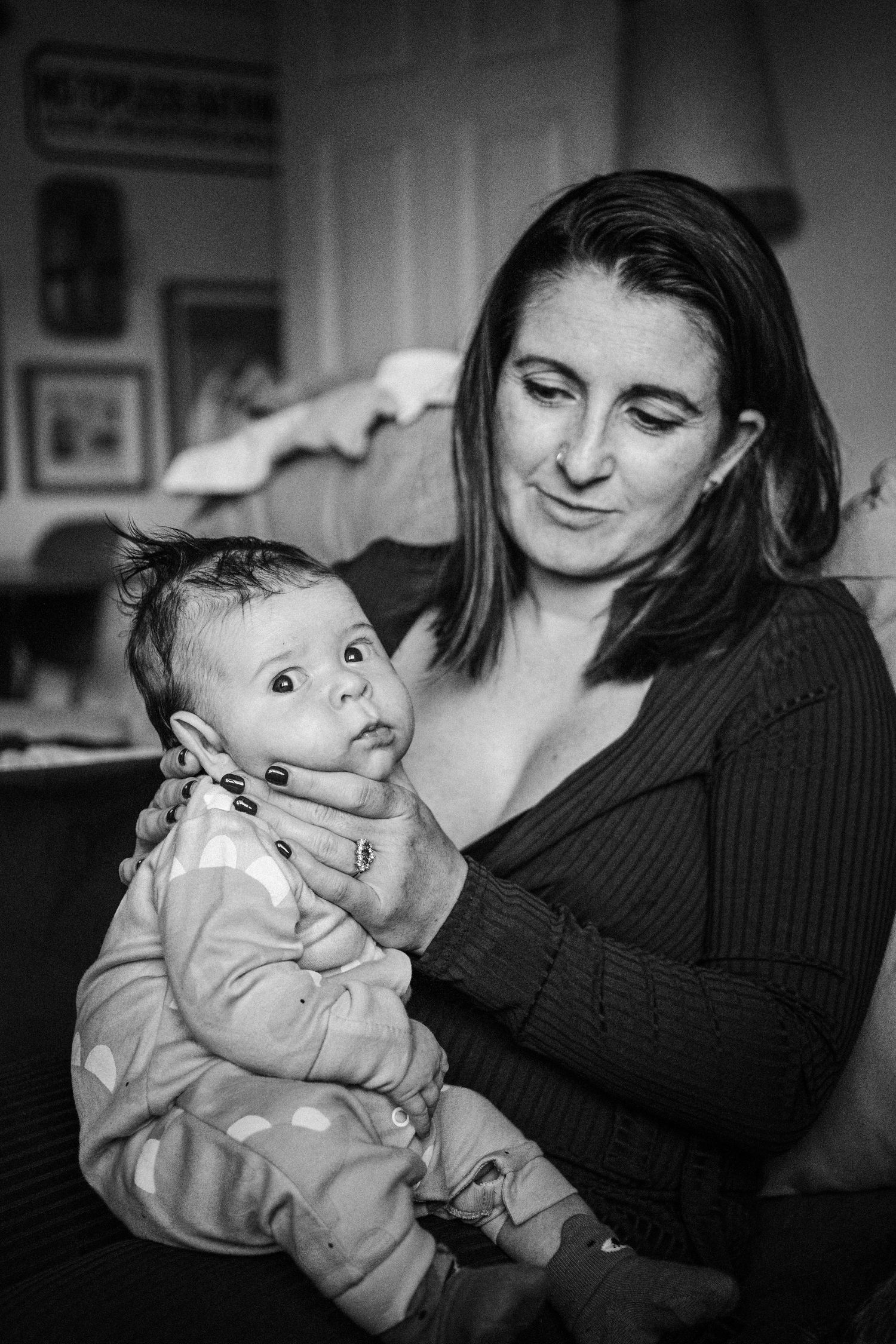 A series of black and white photographs showing tender moments between parent and baby in a cozy home setting.