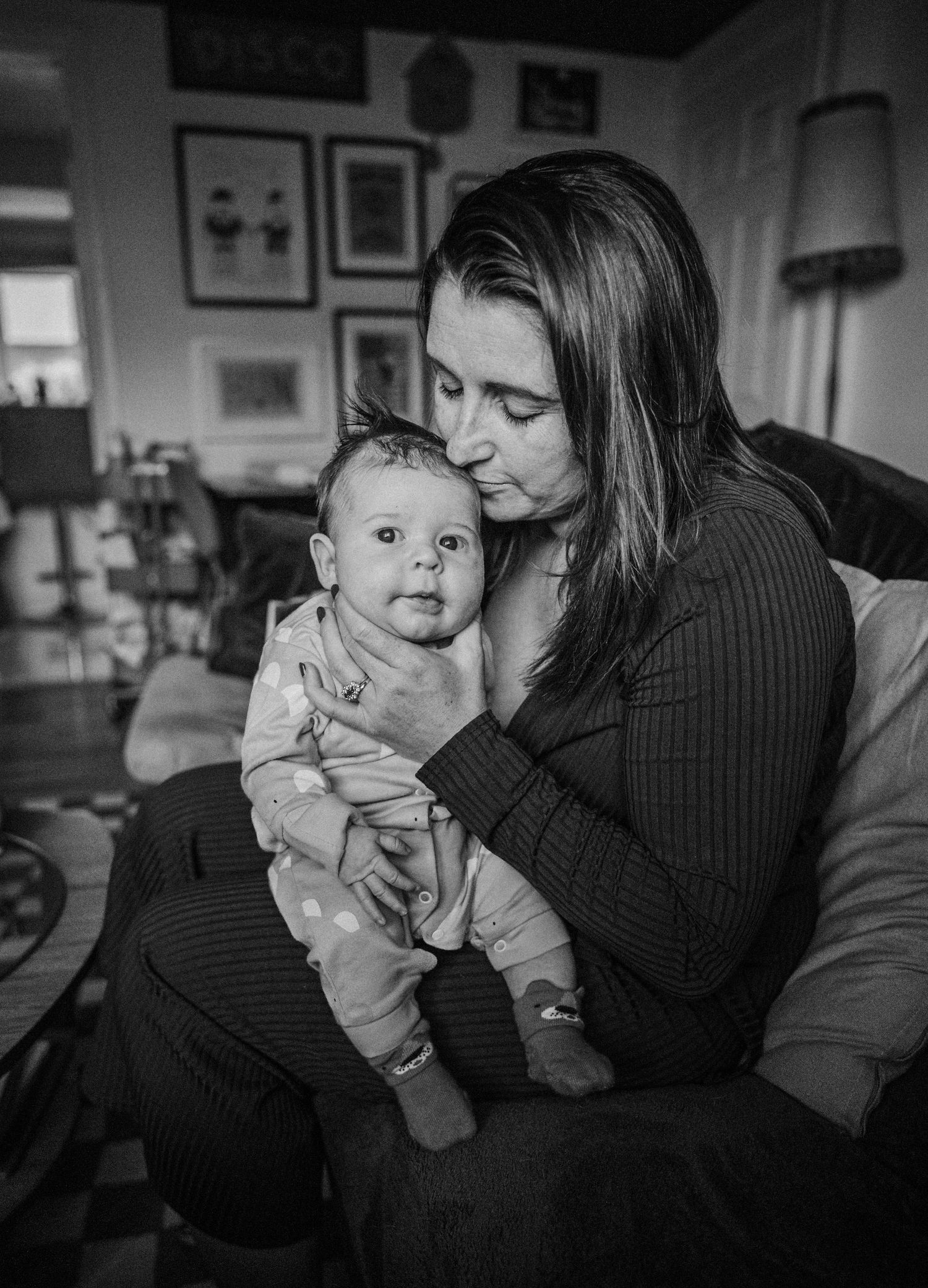 A tender black and white photo series showing intimate moments between a parent and baby in a dimly lit room.