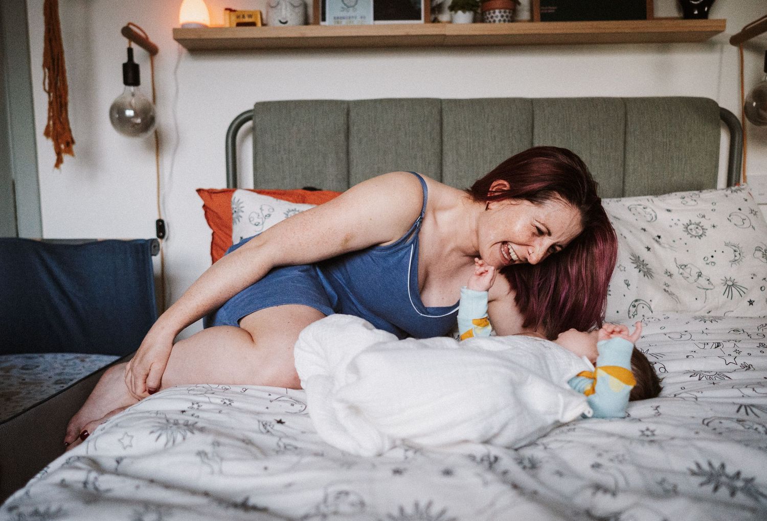 Someone relaxes on a cozy bed with gray bedding in a casual blue tank top while lounging at home.