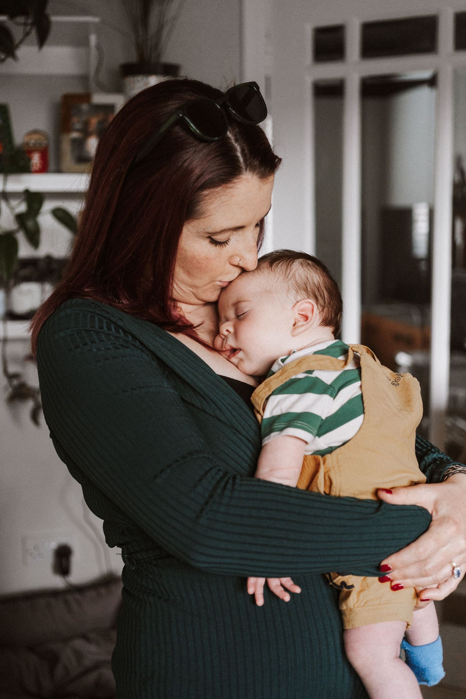 A tender moment captured in black and white as a parent in a green sweater embraces and kisses their young child.