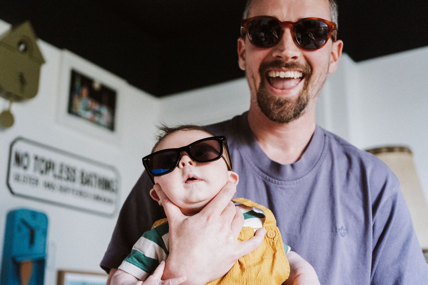 Two people wearing sunglasses smile and laugh together while enjoying a bright sunny day.