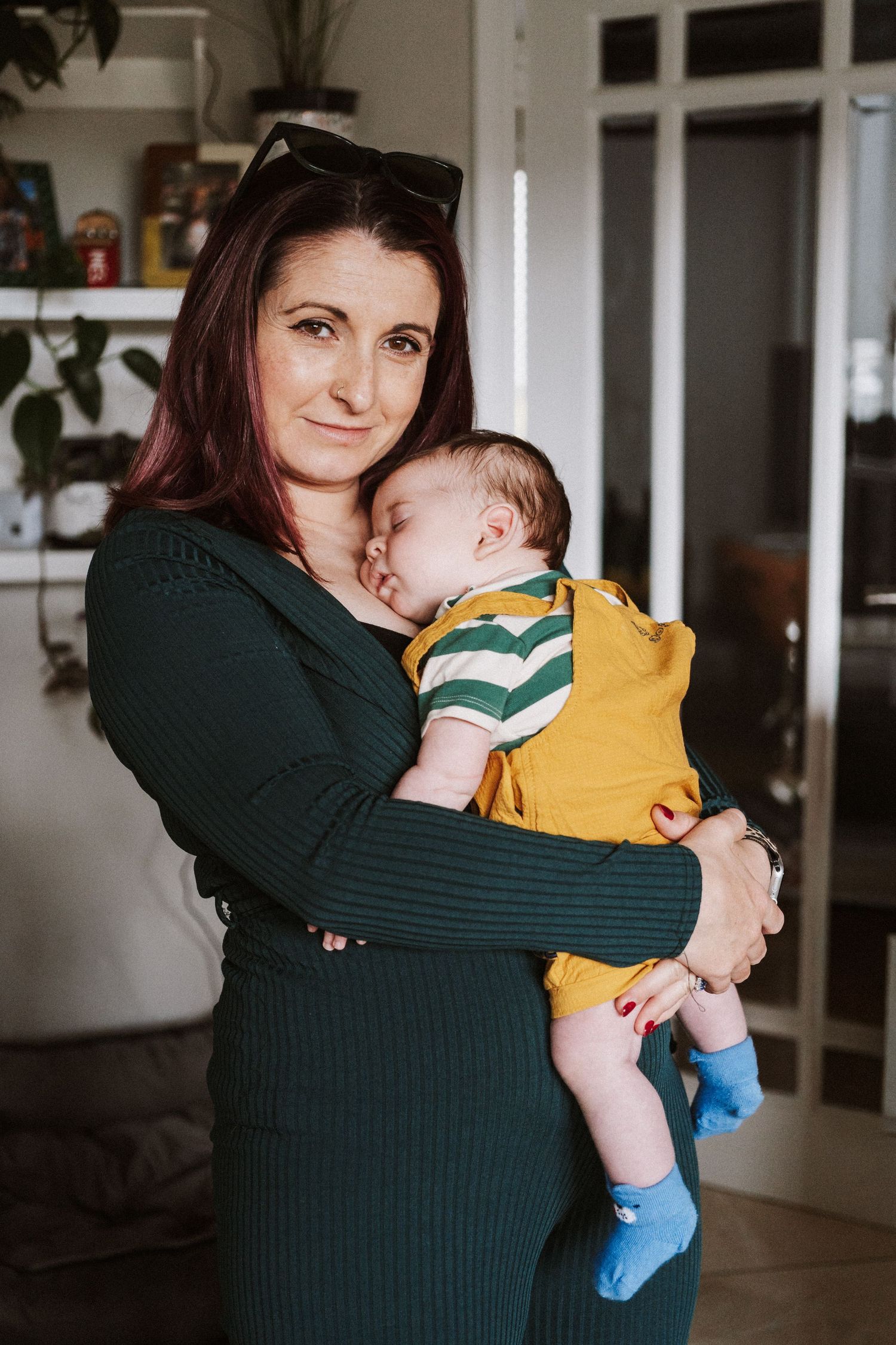 A parent in a dark green sweater holds and comforts a small child wearing a yellow outfit in a series of tender moments.