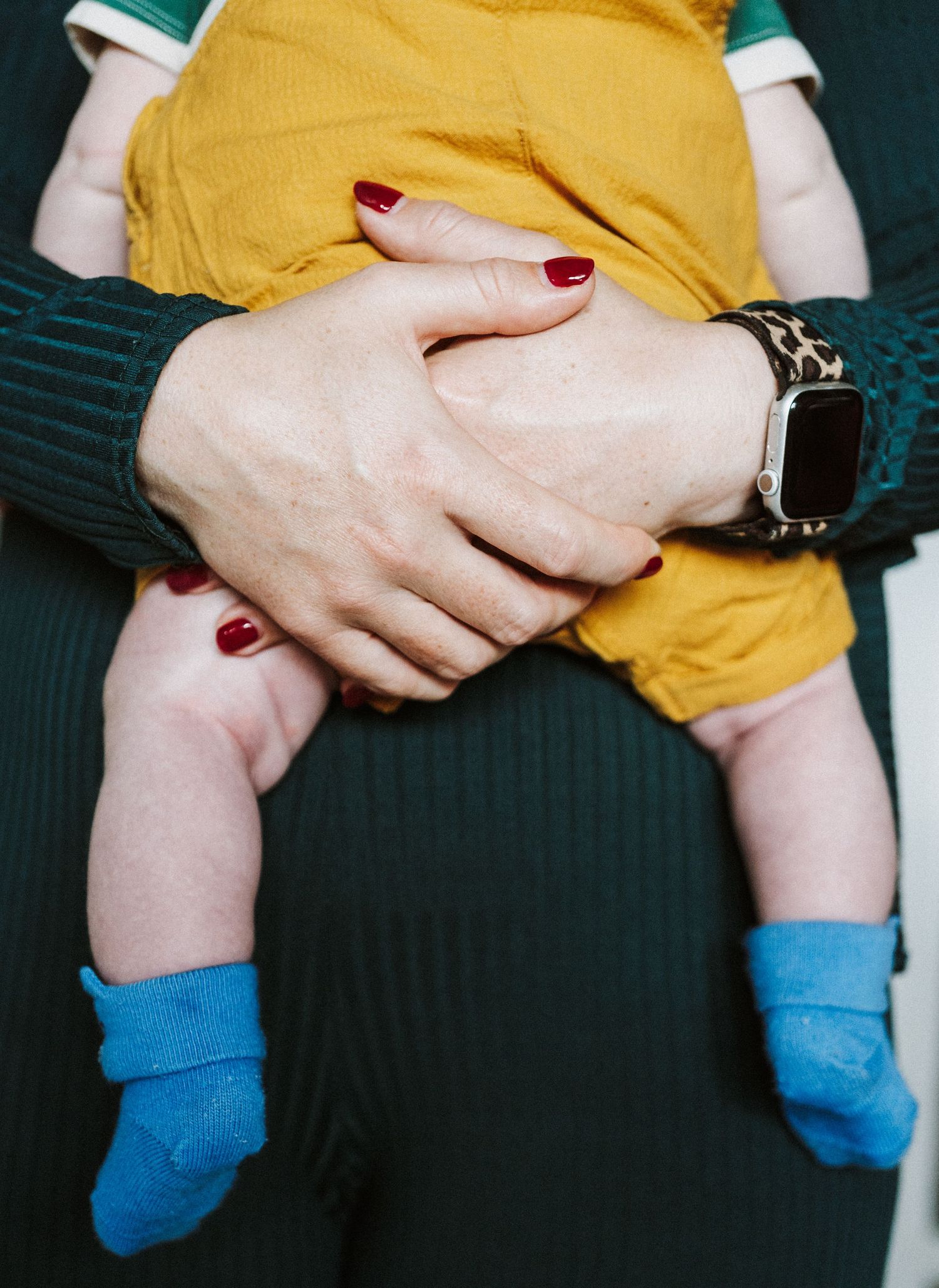 A series of cropped photos showing hands with red nail polish holding onto a yellow fabric against a dark background.