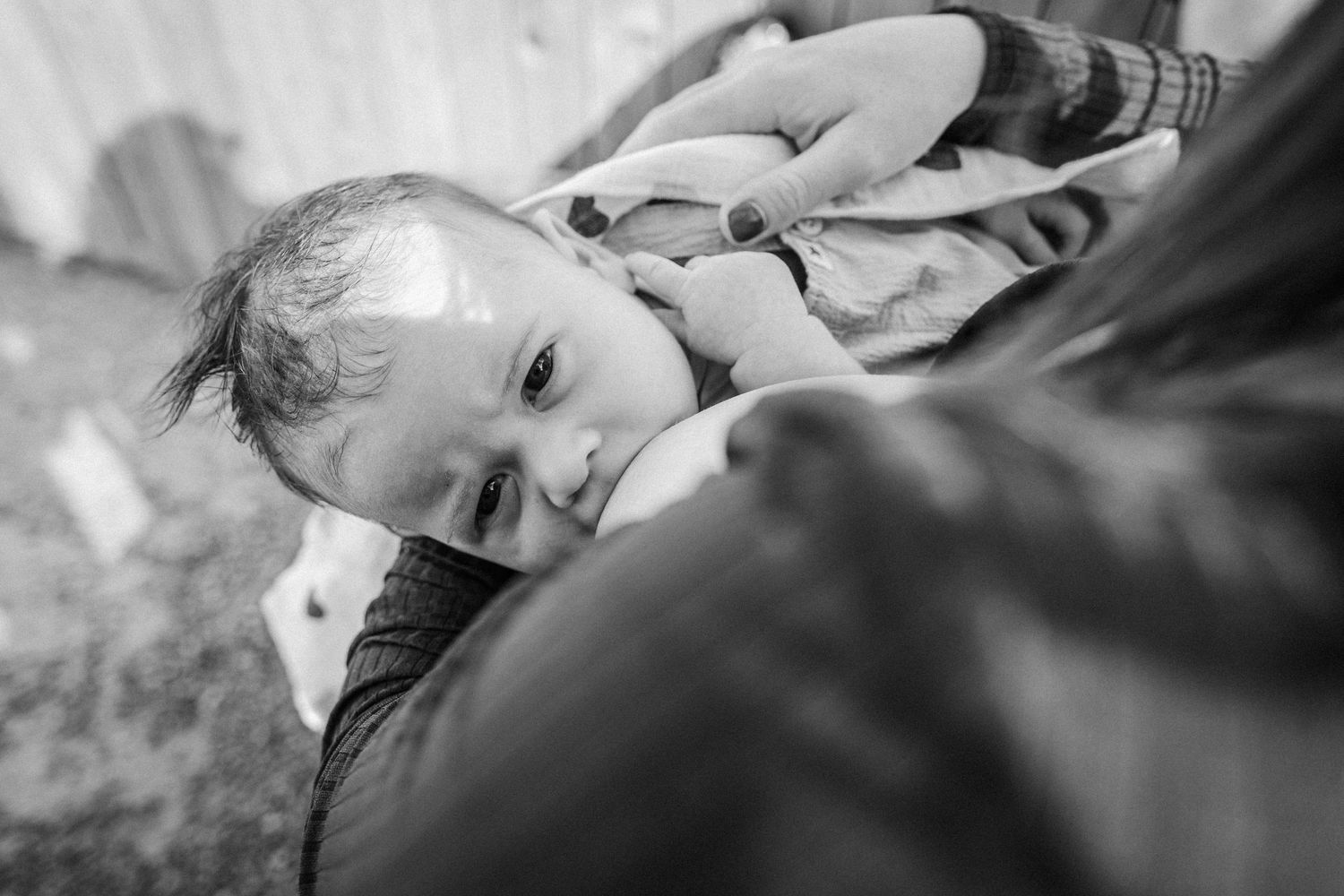 Black and white portrait of a young child resting on someone's shoulder, captured from above in a candid moment.