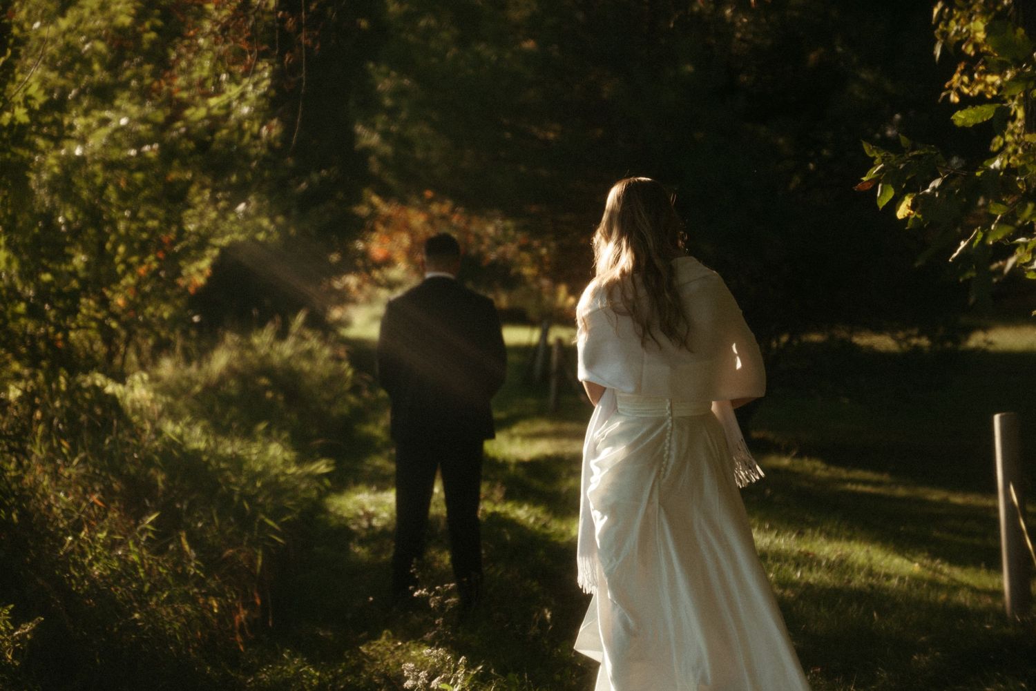 Silhouette of a bride and groom sharing a romantic moment under trees with a serene waterfront backdrop.