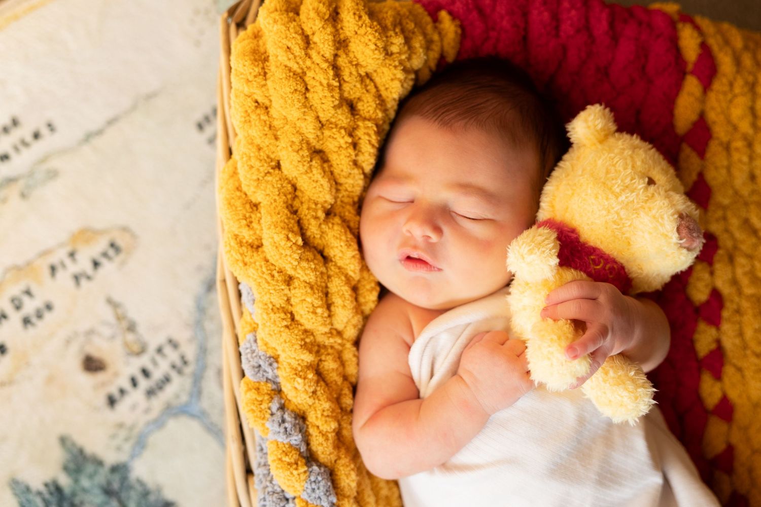 A sleeping baby rests peacefully in a cozy yellow blanket against a soft white background.