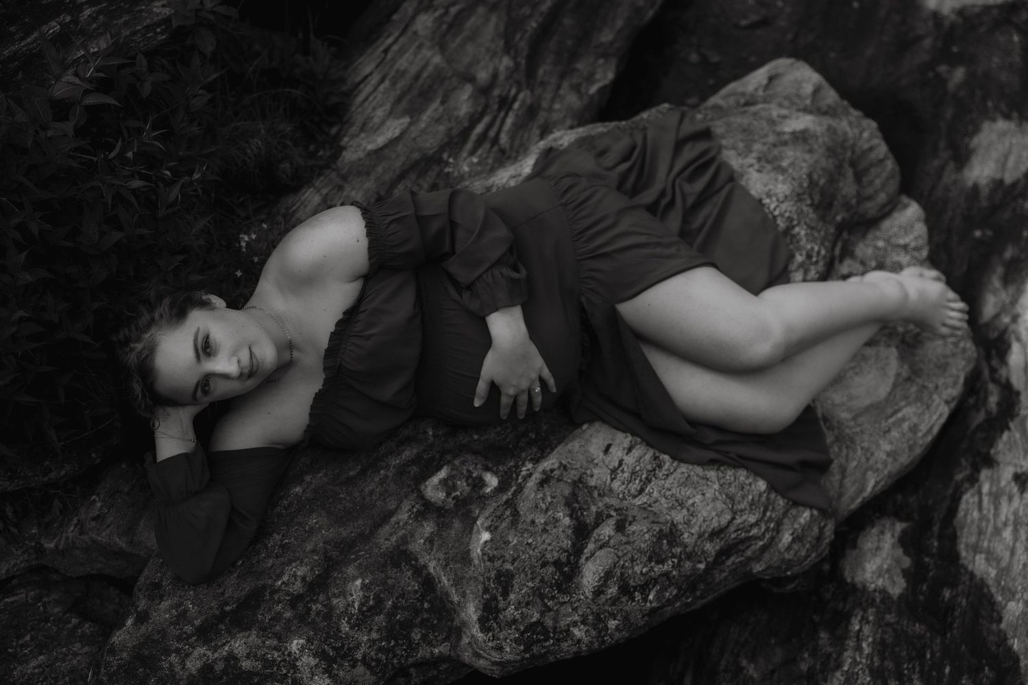 a black and white romantic image of maternity session with firstborn on rocks at state park