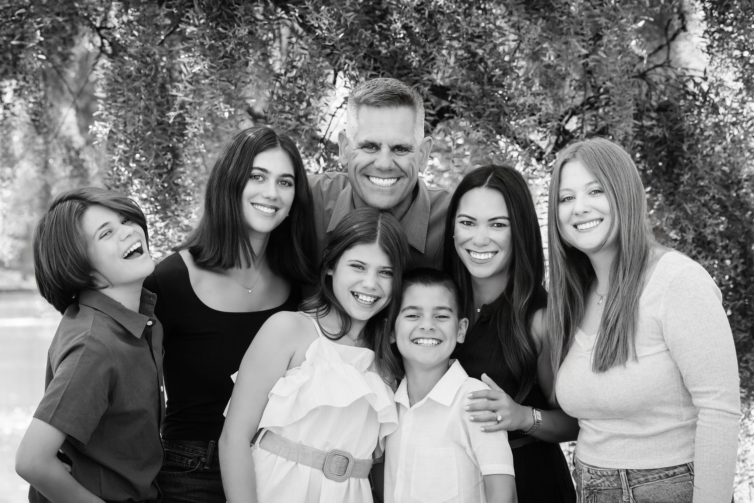 Black and white photo collage showing candid family moments outdoors with natural backgrounds.