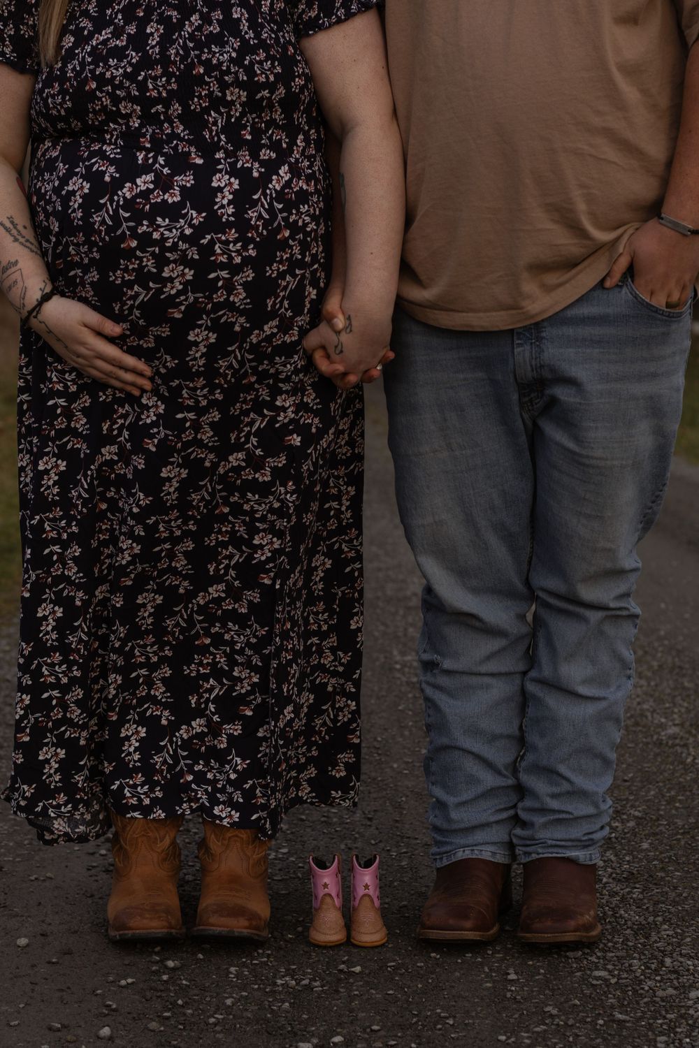 Couple standing with tiny pink cowboy boots between them for maternity photo taken in eatonville washington with local photographer