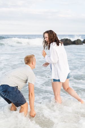 Two people playing and splashing together in ocean waves at the beach on a sunny day.