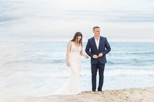 A romantic couple strolling along the shoreline during a beach photoshoot.