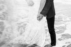A couple in formal wedding attire walks through deep snow during their winter wedding celebration.