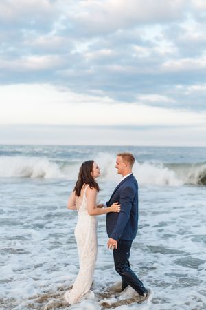 A couple getting splashed by ocean waves during their beach wedding photo session.