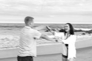 Two people playfully run together on a beach at sunset.