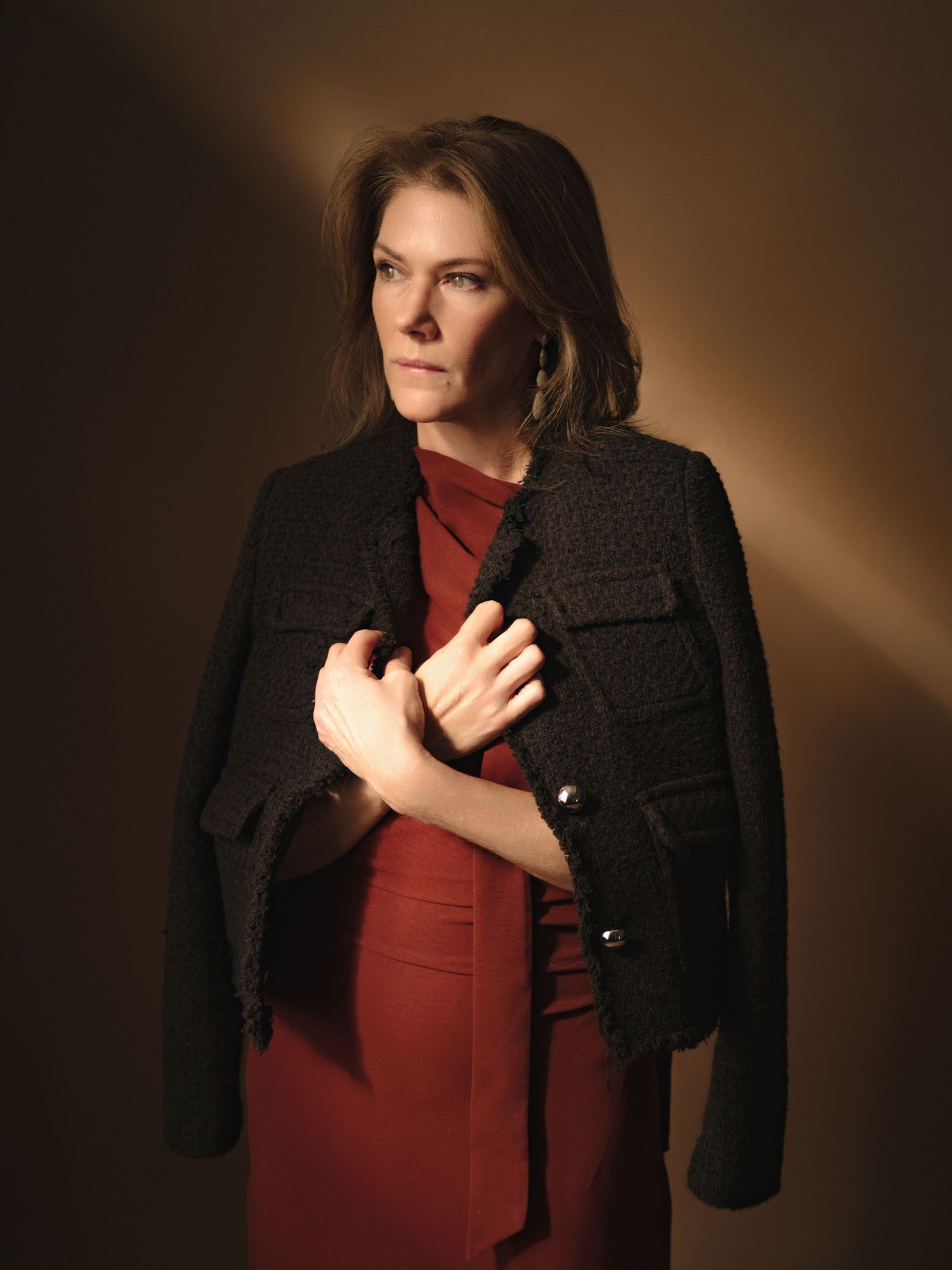 A series of dramatic portrait photos showing a person in a black blazer and burgundy top against a dark background.