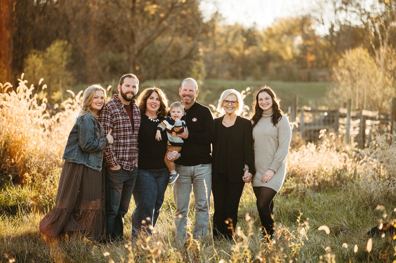 A group of people enjoying golden hour outdoors in casual attire, laughing together in a natural setting.