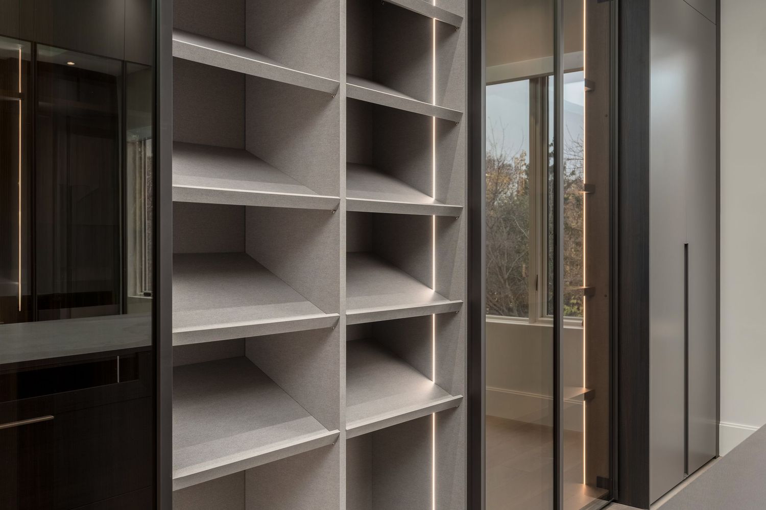 Modern built-in white shelving unit with dark accents and window view in contemporary interior space.
