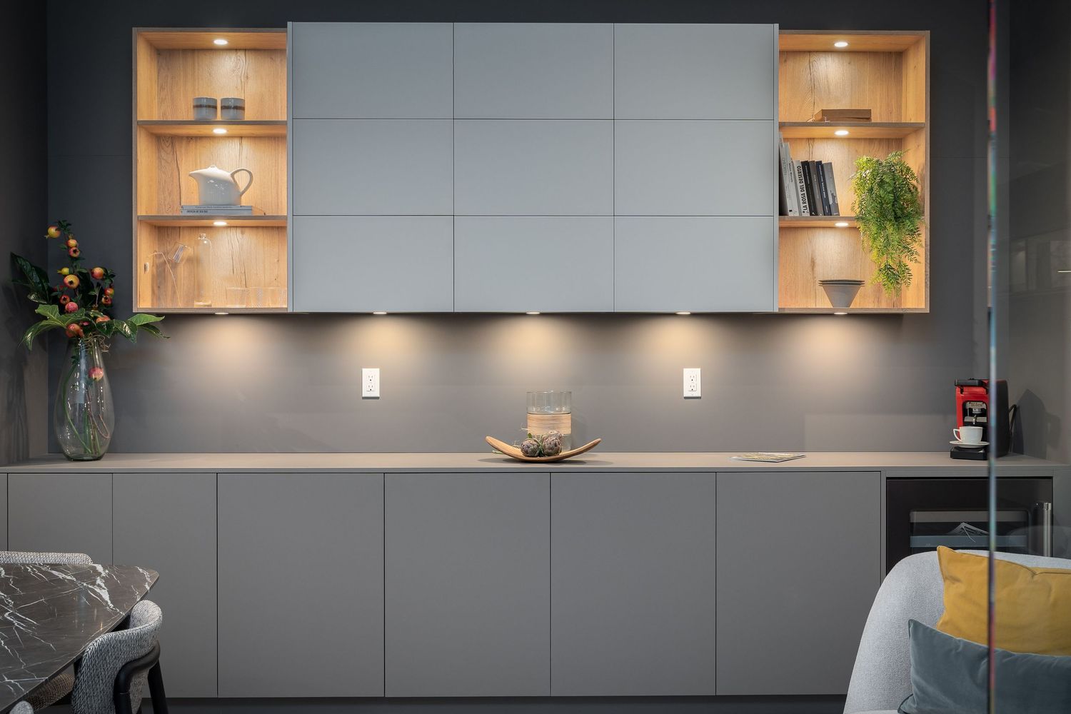 Contemporary kitchen with sleek gray cabinets and built-in LED lighting in wall niches.
