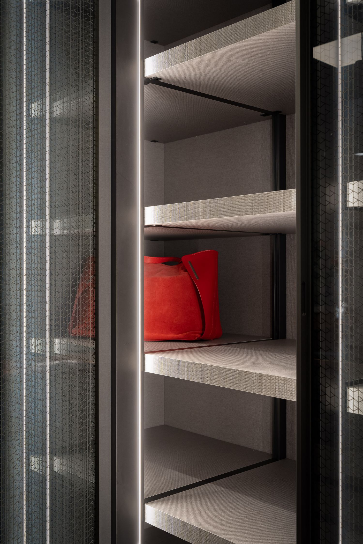 Modern white shelving unit with glass doors and red accent pillows displayed on multiple levels.