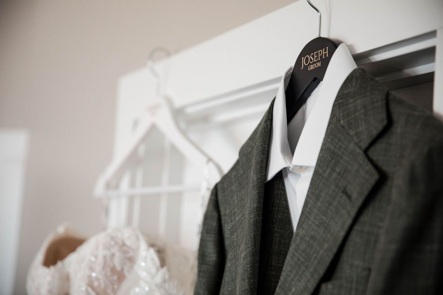 A row of formal black and white tuxedos hanging on a clothing rack in a retail store.