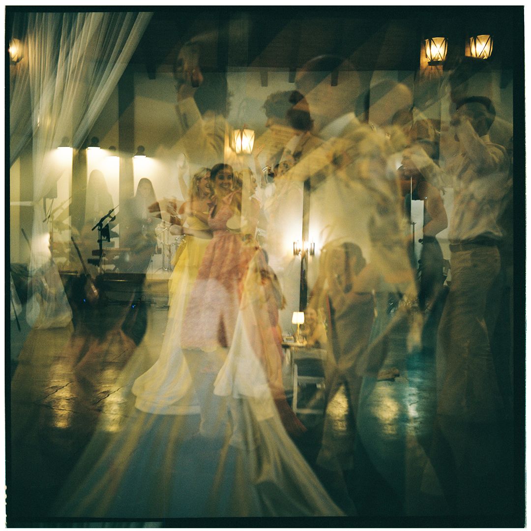 Multiple exposure photograph showing blurred motion of dancers in formal attire moving across a ballroom floor.